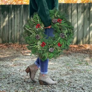 carrying a traditional evergreen wreath