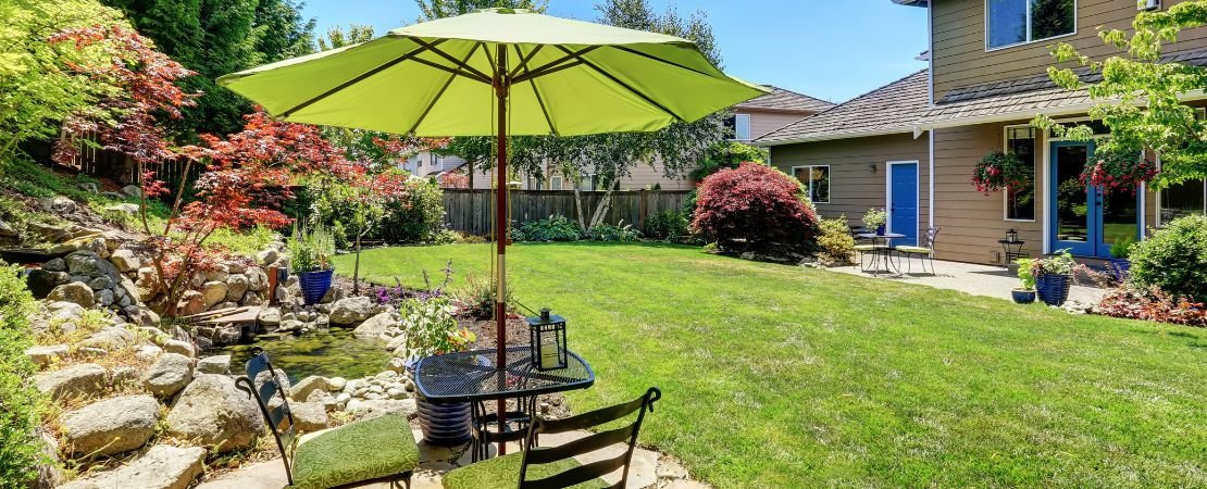 suburban lanscaped backyard with table and green umbrella